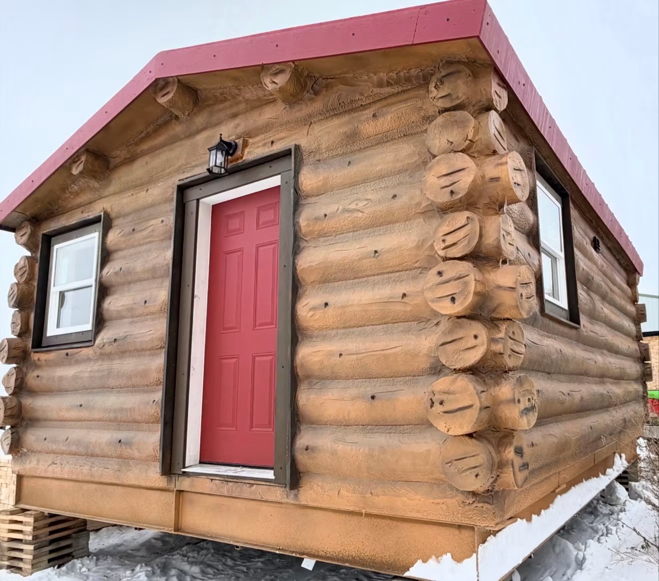 Infinity Capsule log-style home with red steel roof on a steel foundation